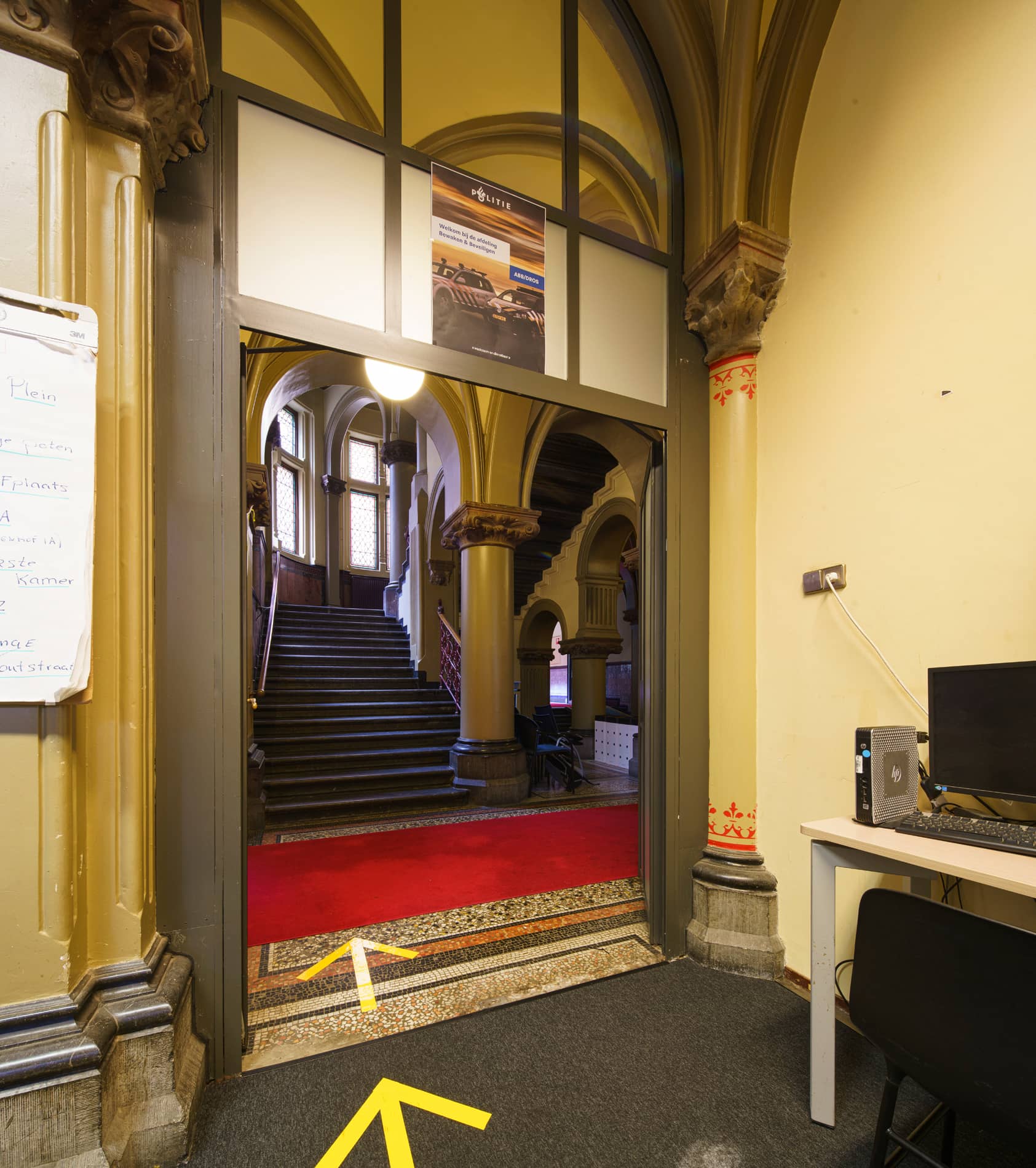 Vestibule gebouw J voor renovatie met werktafel en de doorgang naar het trappenhuis