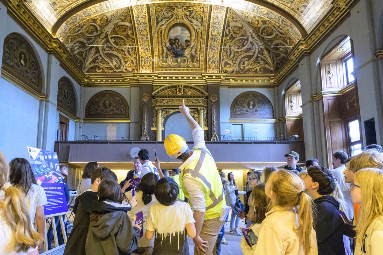 Jonge bezoekers kijken tijdens de Dag van de Bouw 2024 naar het plafond van de plenaire zaal van de Eerste Kamer