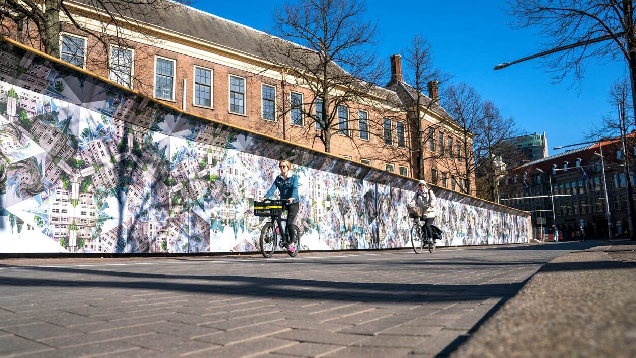 De Escheriaanse bouwschutting aan de Hofweg met op de achtergrond de gebouwen van de Eerste Kamer en de Raad van State