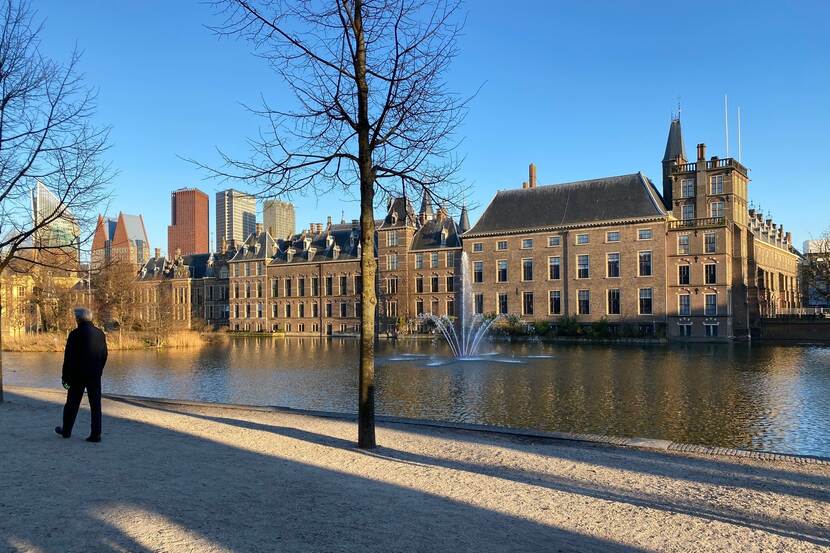 Een man loopt langs de Hofvijver, op de achtergrond de Mauritstoren en de gevel van de Eerste Kamergebouwen