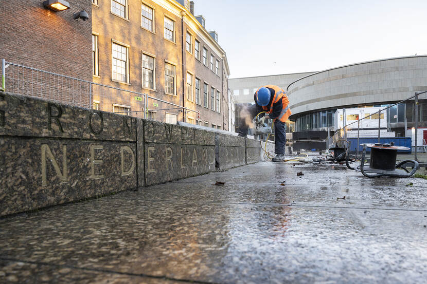 Met een elektrische zagen wordt de marmeren Grondwetbank op de Hofplaats ontmanteld