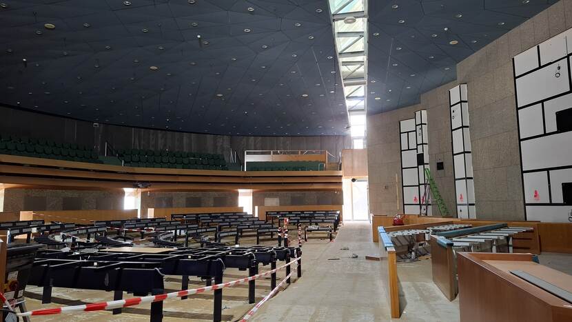 Onttakelde plenaire zaal Tweede Kamer tijdens renovatie; de bankjes zijn verwijderd, het kunstwerk is ingepakt, de lichtstraat tussen 'vak K' en de 'tribune' in het dak is zichtbaar