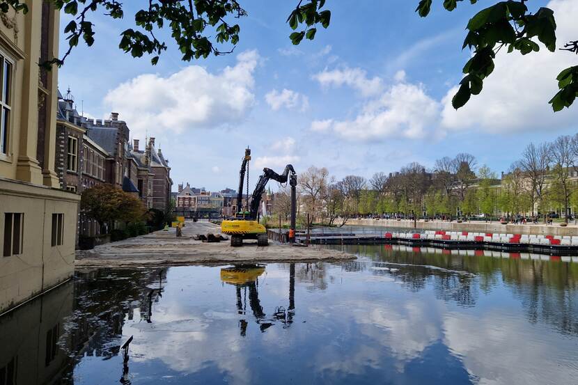 Aanleg van het werkgebied Hofvijver; een installatie is bezig damwanden te plaatsen langs het met zand gedempte gedeelte van de vijver