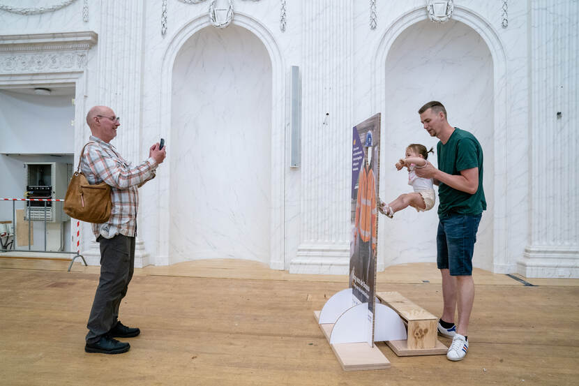 Vader houdt kind omhoog in Oude Zaal Tweede Kamer - Dag van de Bouw / Dag van de Architectuur op het Binnenhof - 17 juni 2023