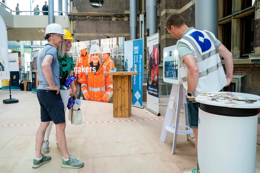 Bezoekers poseren met bouwhelm voor fotoapparaat in de Statenpassage - Dag van de Bouw / Dag van de Architectuur op het Binnenhof - 17 juni 2023