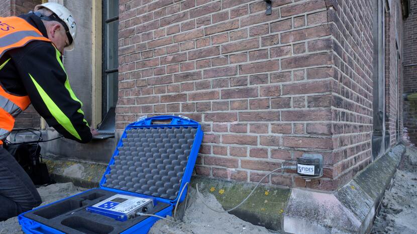 Een medewerker van Fides is de meetapparatuur bij het Eerste Kamergebouw aan het instellen