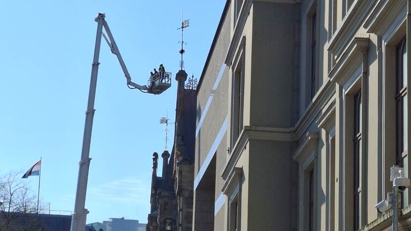 Drie bouwmedewerkers op een hoogwerker bij het dak van gebouw J van de Tweede Kamer