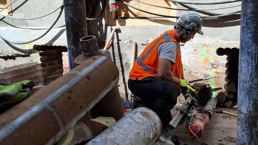 Werknemer bezig met gaten boren onder maaiveld