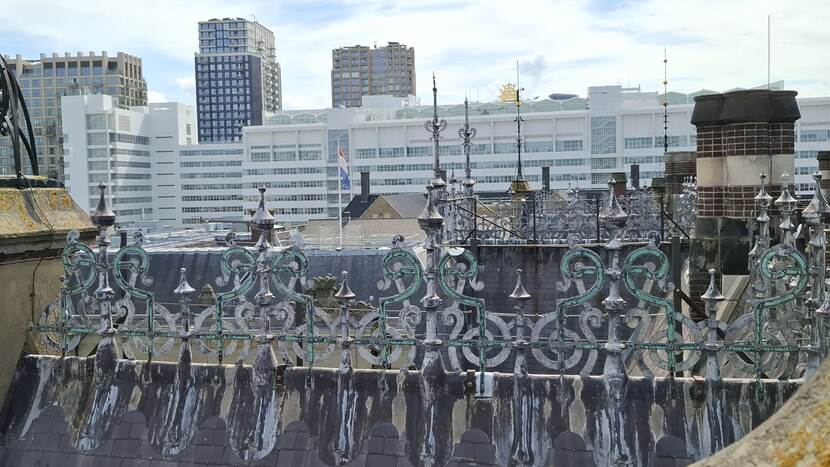 Daknok van gebouw J met smeedijzeren nokvorsten, op de achtergrond het gemeentehuis van Den Haag