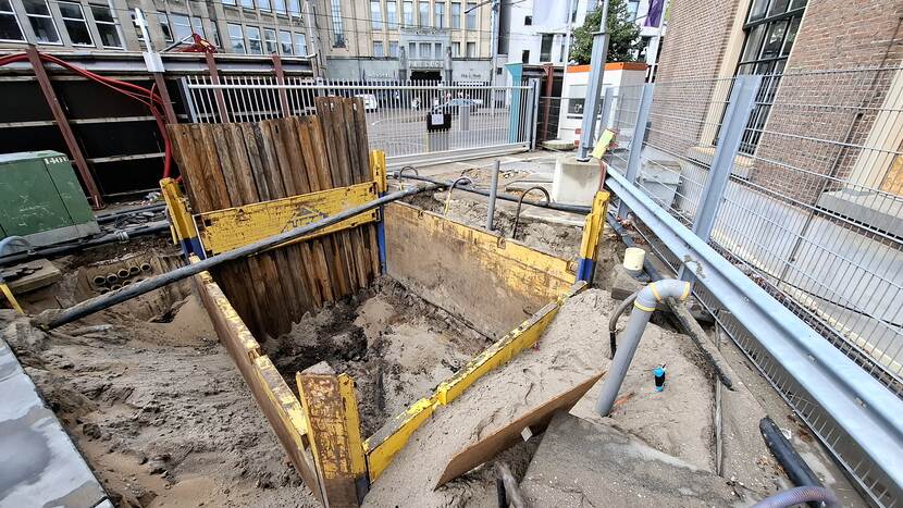 Afgezet gat in de grond met op de achtergrond het toegangshek van de bouwplaats aan de Hofweg