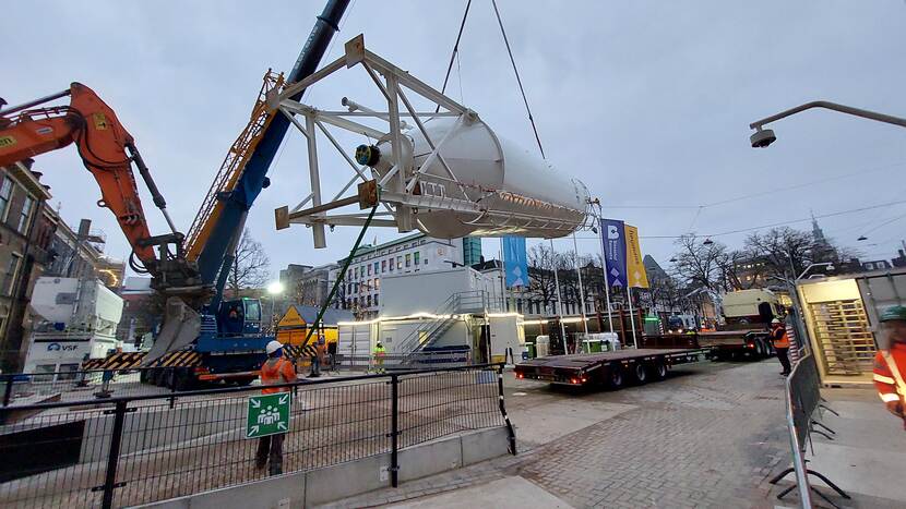 Cementmixer wordt met een mobiele hijskraan op een dieplader gehesen