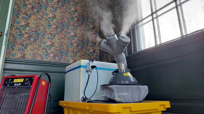 Luchtbevochtiger met drie pijpjes waaruit waterdamp spuit naast een elektrisch verwarmingsapparaat