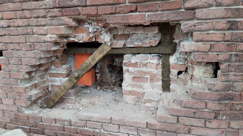 In een bakstenen muur is een gat gemaakt waarachter een muuranker zichtbaar is