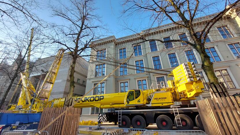 Een gele mobiele kraan staat nog ingeklapt voor gebouw K (Koloniën)