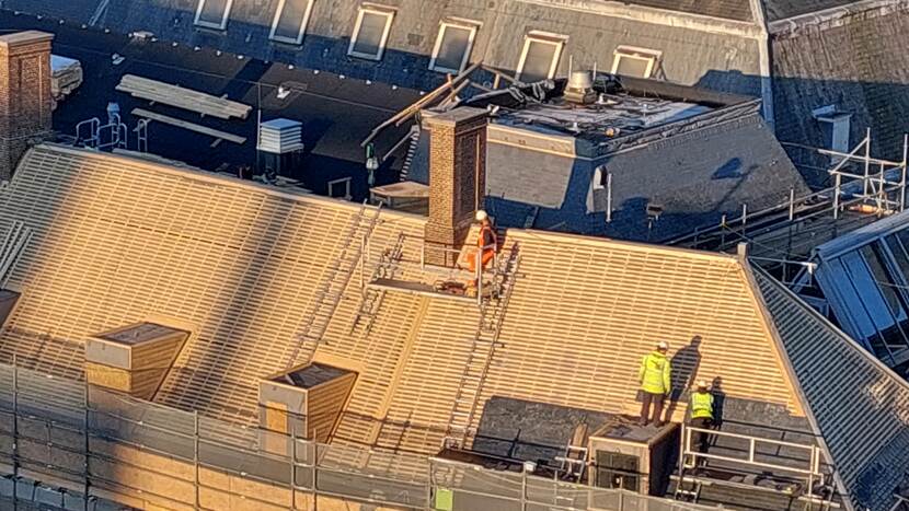 Drie mensen aan het werk op het dak van gebouw A van de Tweede Kamer