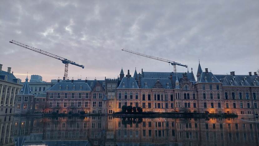 Zicht op de Hofvijvergel bij avondlicht, op de achtergrond torenen de kranen boven het Binnenhof uit