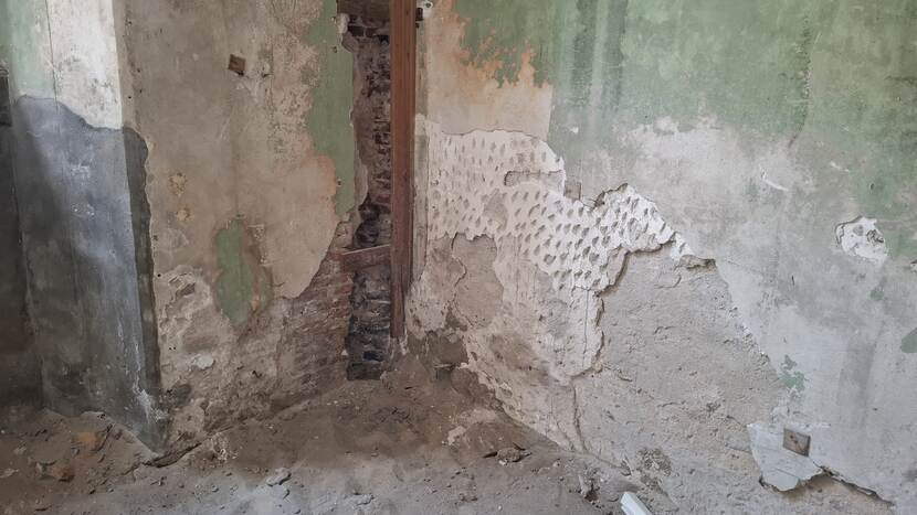 Hoek van kamer in de Raad van State met kapot stucwerk, waarin de verschillende lagen zijn terug te zien