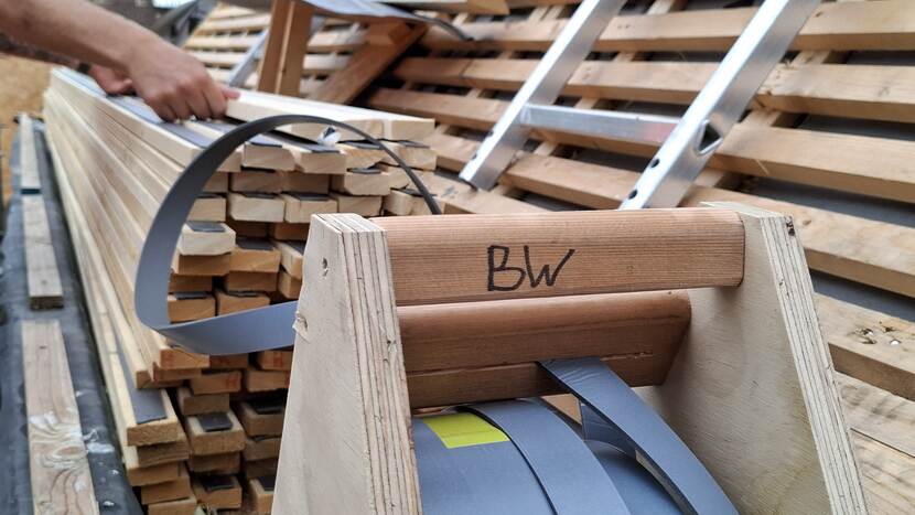 Stroken met foam worden vanaf een rol op tengellatten geplaatst bij gebouw C van de Tweede Kamer