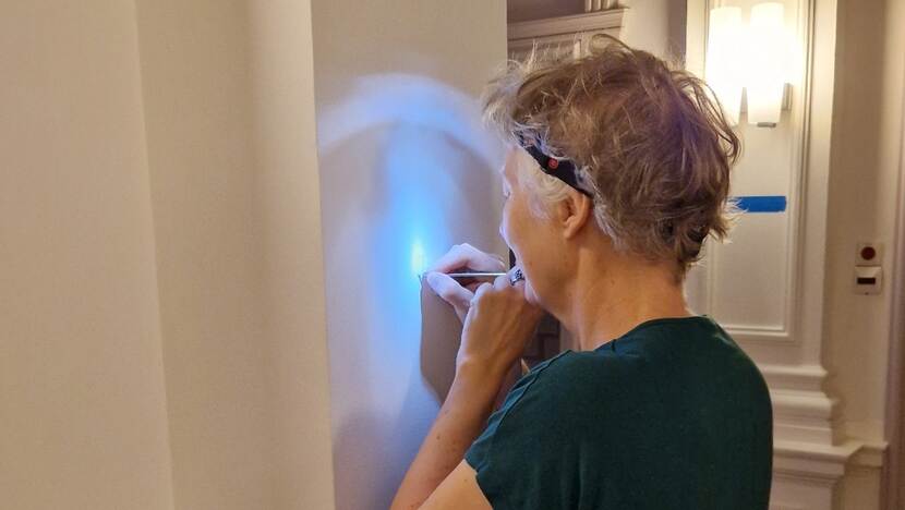 Medewerker bezig met afkrabben van een verflaag in het ministerie van Algemene Zaken