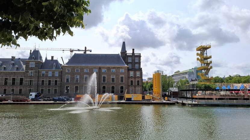 Werkgebied Hofvijver bij de spiegelende bouwkeet, met op het werkgebied twee gele silo's en een aantal gele containers