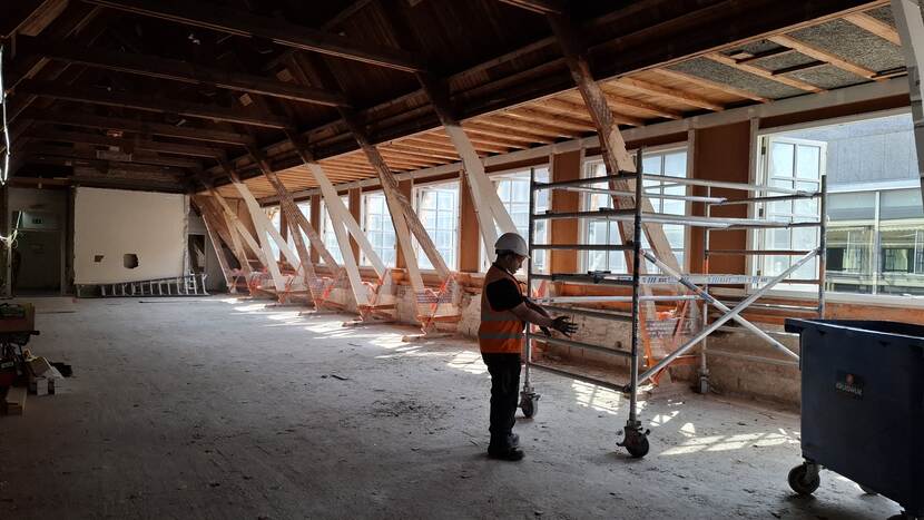 Bouwmedewerker bij steiger op lege zolder van gebouw C van de Tweede Kamer