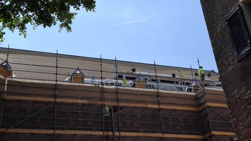 Steiger bij gebouw C van de Tweede Kamer waarop aan het dak wordt gewerkt