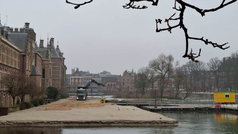 Een brede strook zand in de Hofvijver langs de gevels van het Binnenhof