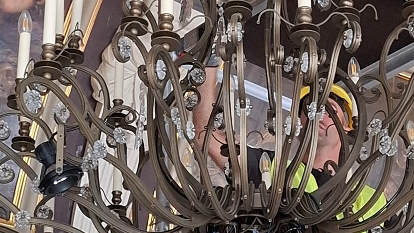 Medewerker op een steiger bij een kroonluchter in de Trêveszaal
