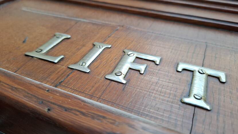 Met schroeven op deur bevestigede metalen letters 'LIFT'