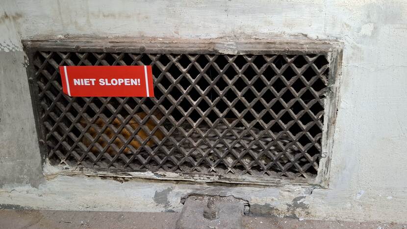 Gat met rooster en daarop een sticker met opschrift 'niet slopen'