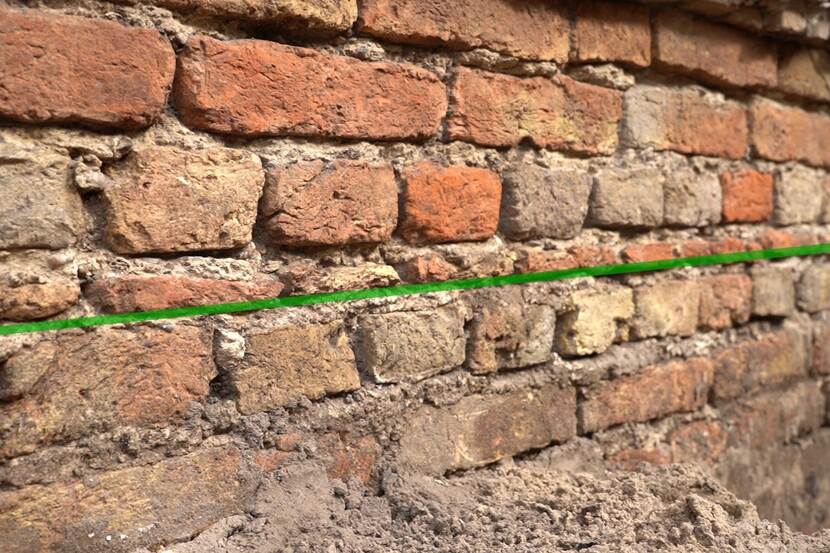 Beeld van de baksteenlagen van het fundament. Met een groene lijn is de ‘varkenslaag’ aangegeven die aanzienlijk dunner is dan de andere baksteenlagen.