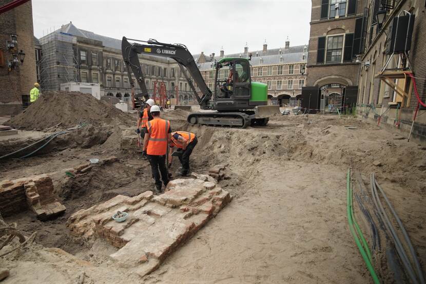 Archeologen aan het werk in een ondiepe kuil met resten van muren van de Hofkapel