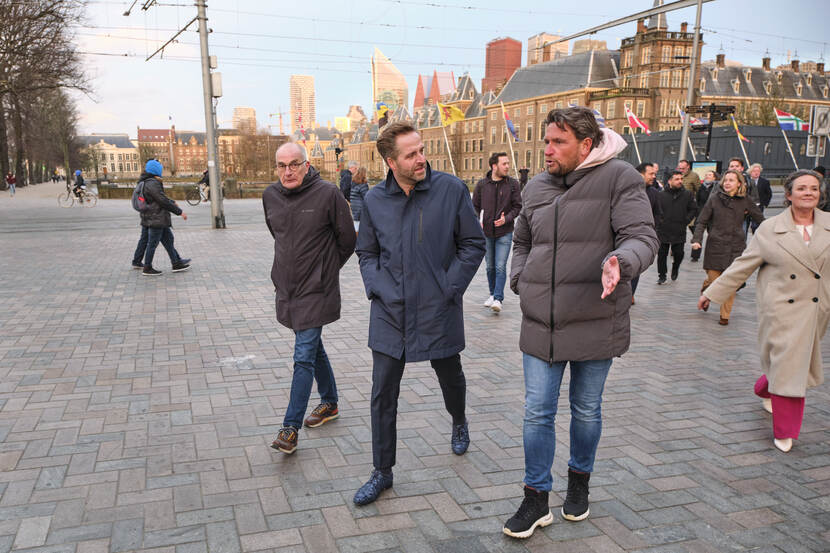 Minister Hugo de Jonge loopt samen met ondernemers en omwonenden over de Plaats naar het Informatiecentrum Binnenhof Renovatie. Op de achtergrond de Hofvijver en het Binnenhof