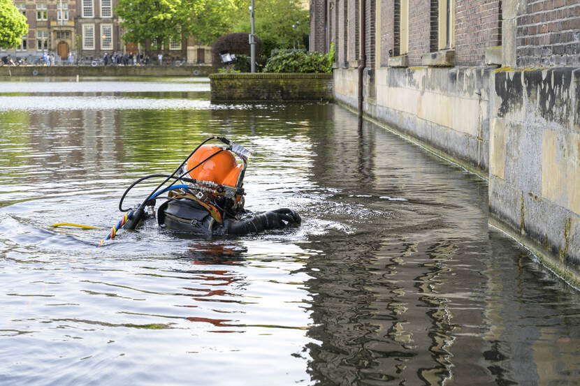 Een duiker met oranje helm in de Hofvijver bij het Eerste Kamergebouw