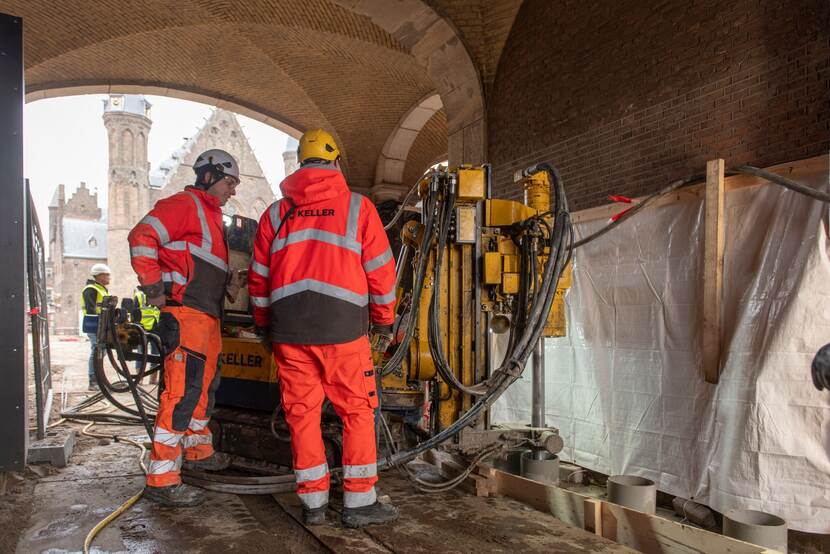 Compacte groutinstallatie in de Stadhouderspoort, met op de achtergrond de Ridderzaal. Te zien zijn de groutkolommen, in een daarvan perst de installatie de groutsuspensie