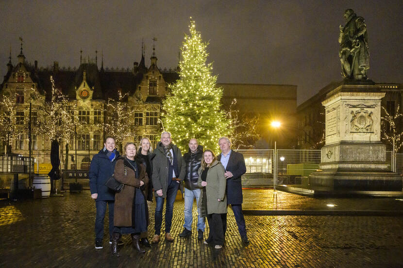 De verlichte kerstboom op het Plein naast het standbeeld van Willem van Oranje. Voor de kerstboom staan de leden van het Kernteam Omgeving Binnenhof; v.l.n.r. Peter Stokman (gemeente Den Haag), Mary Hessing (programmeur The Hague & Partners), Eveline Braam (omgevingsmanager Rijksvastgoedbedrijf), Ad Dekkers (directeur Bureau Binnenstad), Bas Winkler (voorzitter bestuur Binnenstad in Bedrijf), Monique van der Bijl (coördinator team omgeving en communicatie Rijksvastgoedbedrijf), Ton Kroeze, (voorzitter ondernemersvereniging Pleinkwartier)