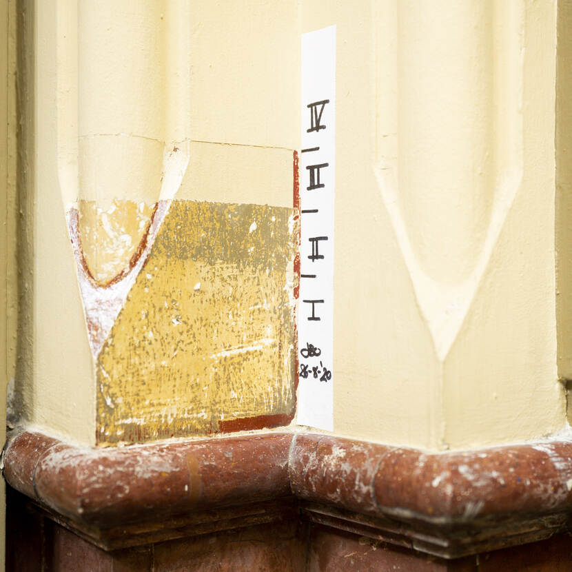 Detail van een  kijkvenster met verschillende verflagen op natuurstenen basement van een zuil