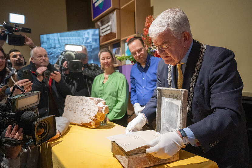 Burgemeester Jan van Zanen opent met witte handschoentjes de tijdcapsule, met naast het Patrick Bosman en Sophie Olie