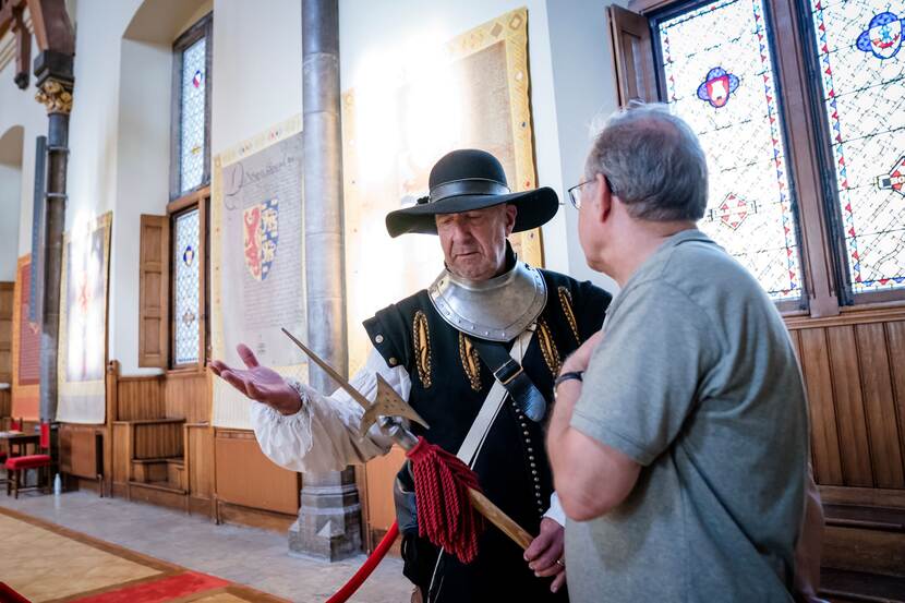 Een acteur verkleed als poortwachter met een bezoeker in de Ridderzaal op Open Monumentendag Binnenhof 2023