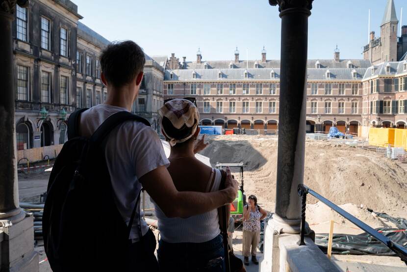 Twee bezoekers kijken uit over het zand op het Opperhof bij de uitgang van de Ridderzaal op Open Monumentendag Binnenhof 2023