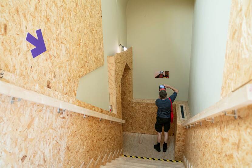 Bezoeker neemt een foto onderaan een afgetimmerde trap in het Eerste Kamergebouw op Open Monumentendag Binnenhof 2023