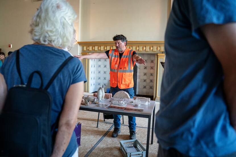 Een archeoloog geeft uitleg achter een tafel met archeologische vondsten op Open Monumentendag Binnenhof 2023