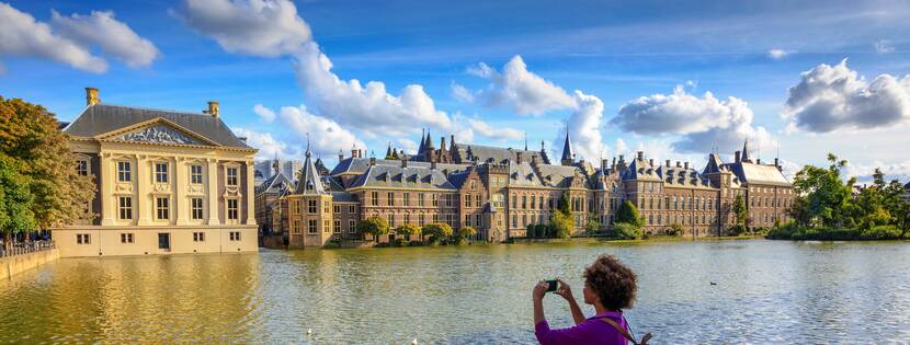Afbeelding: een toerist fotografeert het Mauritshuis bij de Hofvijver