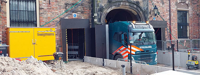 Een elektrische vrachtwagen rijdt vanaf het Binnenhof door de Stadhouderspoort