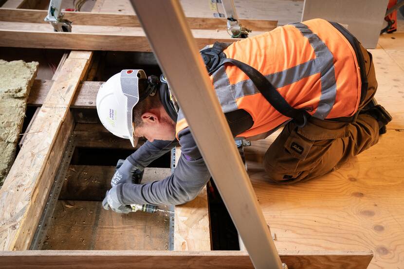 Installateur aan het boren bij gat in de vloer van de Tweede Kamer