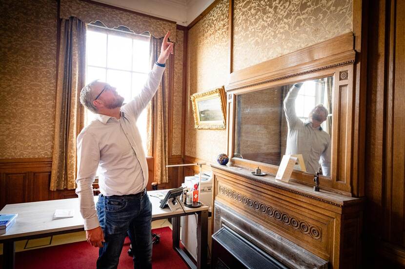Bouke Wolbrink in de griffierkamer van de Eerste Kamer wijzend naar het plafond