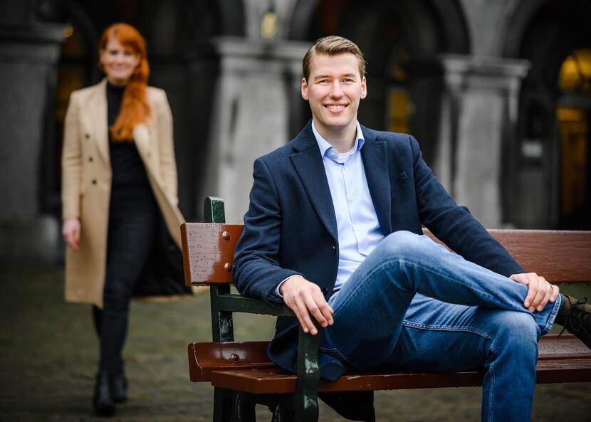 Bram Hulshof zittend op een bank met achter hem Marleen Greil