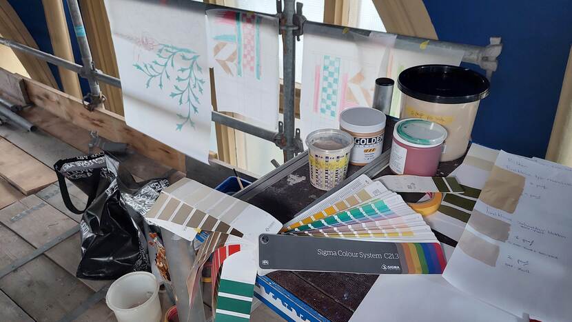 Werktafel op de steiger in het trappenhuis met verf, kleurwaaiers en kleurproeven